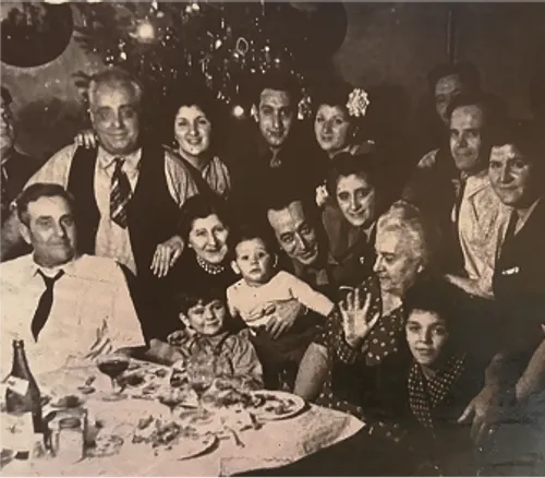 Vintage family photo showing multiple generations gathered around a festive dinner table, reflecting the family bonds and communal spirit that inspired Anna’s Vesuviano in Providence, Rhode Island